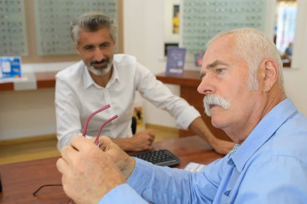 Oudere cliënt probeert nieuwe frames aan de opticien — Stockfoto