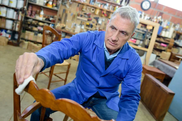 Senior man polishing wooden chair — Stock Photo, Image