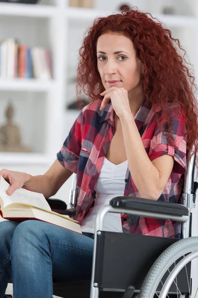 Behinderte junge Frau im Rollstuhl liest Buch — Stockfoto