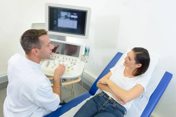 El doctor se sentó en la máquina de ultrasonido hablando con el paciente — Foto de Stock