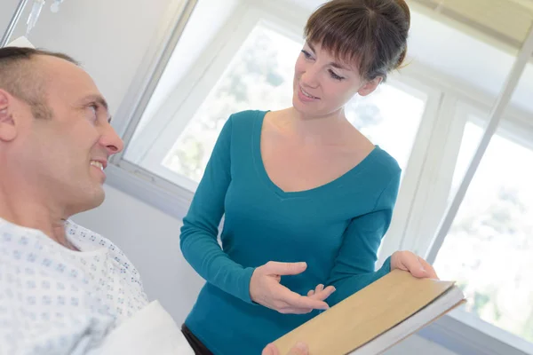 Girl giving a book to the patient — Stock Photo, Image