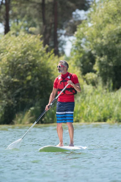 Homme profiter d'une balade sur le lac avec planche à pagaie — Photo
