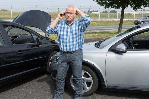Пенсионер в отчаянии по телефону после аварии — стоковое фото