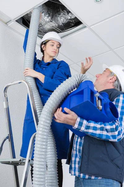 Eletricista feminino instalar tubo ac no teto com mestre trabalhador — Fotografia de Stock