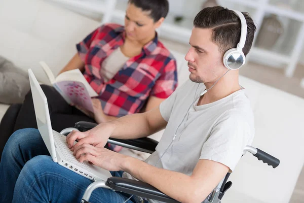 Hombre discapacitado usando el ordenador portátil sentado junto a su novia —  Fotos de Stock