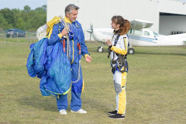 Man och kvinna i airodrome holding fallskärm — Stockfoto