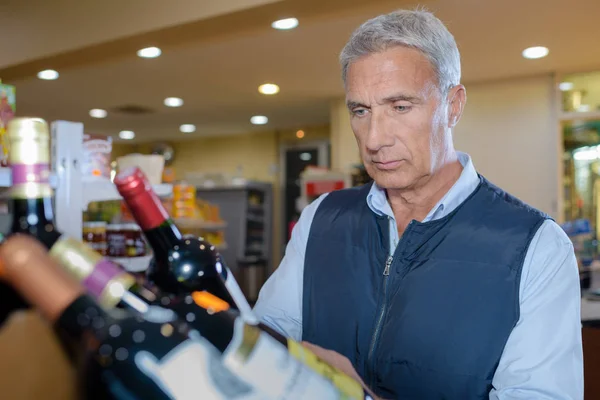 Dojrzały mężczyzna, trzymając butelkę wina — Zdjęcie stockowe