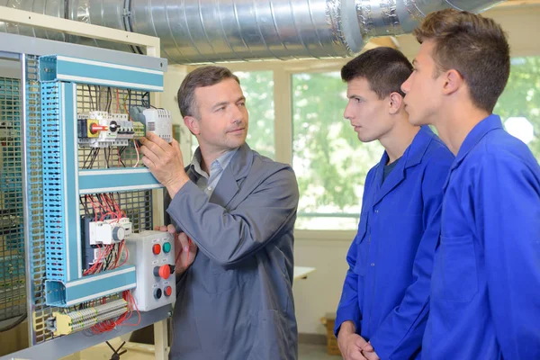 Profesor ayudando a los estudiantes a capacitarse para ser electricistas —  Fotos de Stock