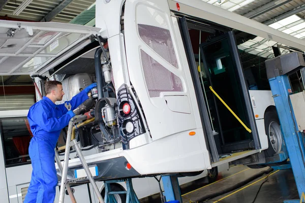 Mechanic working on engine of public transport bus