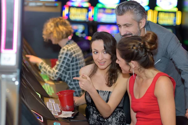 Hermosa gente joven cerca de la máquina tragaperras en un casino —  Fotos de Stock