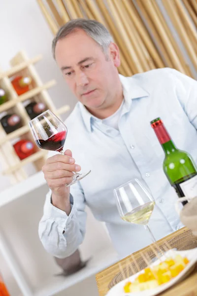 Älterer Mann trinkt zu Hause ein Glas Rotwein — Stockfoto