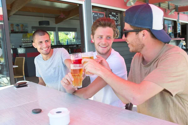 Tres amigos varones felices bebiendo cerveza en la terraza del restaurante —  Fotos de Stock