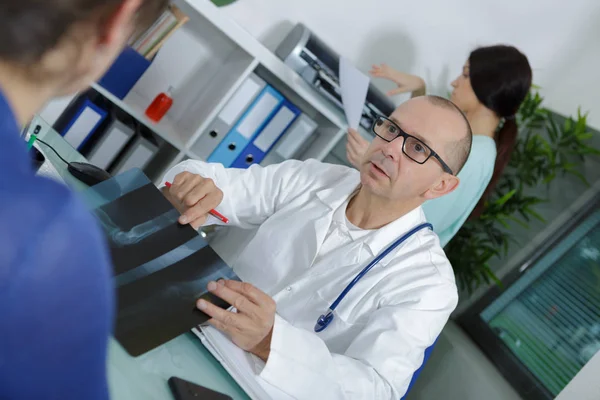 Чоловічий радіолог розмовляє з пацієнтом про рентгенівський знімок — стокове фото