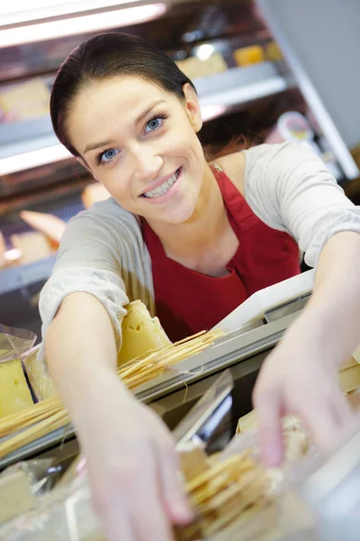 Vendedor morena feliz com diferentes tipos de queijo — Fotografia de Stock