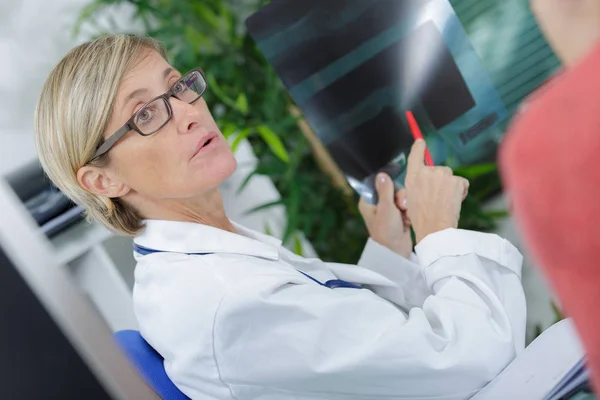 Ärzte zeigen auf Röntgenbild ihrer Patientin in Klinik — Stockfoto