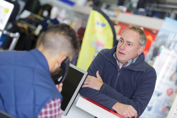 Mann wird ungeduldig, während Ladenbesitzer telefoniert — Stockfoto