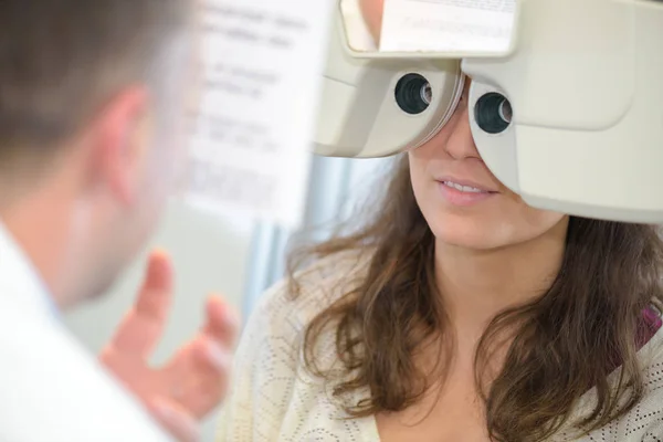Пациентка смотрит через фотоптер во время осмотра глаз — стоковое фото