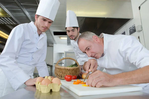 Apprentis regardant chef cuisinier garnir un plat — Photo