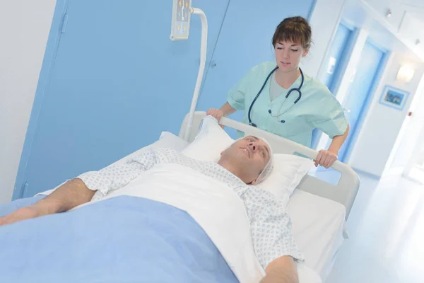 Verpleegkundige duwen patiënt in zijn bed — Stockfoto