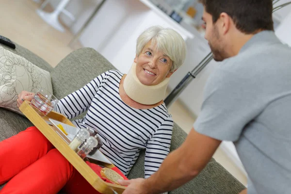 Aiuto domestico che serve la sua tavola calda alla donna ferita più anziana — Foto Stock