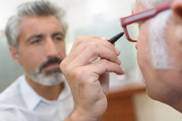 Optiker använder och oftalmoskop för att undersöka en patienter ögon — Stockfoto