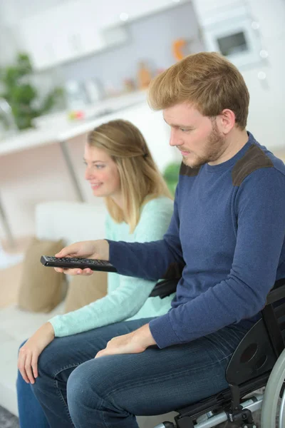 Behinderter Mann vor dem Fernseher mit seiner schönen Frau — Stockfoto