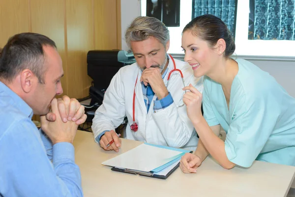 Leende kvinnlig sjuksköterska med läkare och patient — Stockfoto