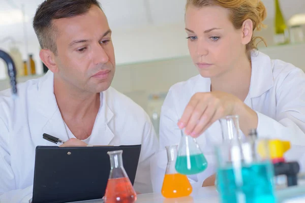 남성과 여성의 실험실 기술자 다채로운 액체를 보고 — 스톡 사진