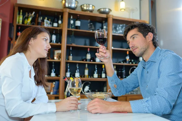 Homem no restaurante levantando vinho para olhar para o vinho — Fotografia de Stock