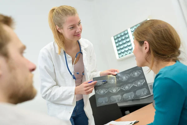 Médico feliz leitura xray resultados para casal — Fotografia de Stock