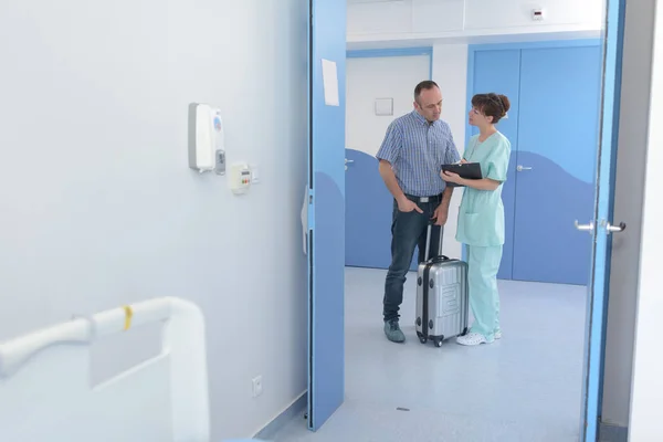 Homme avec valise parler à infirmière dans le couloir — Photo
