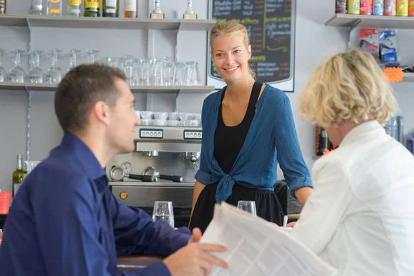 微笑的女咖啡师与两个客户在柜台 — 图库照片