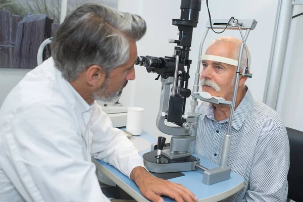 Opticien Masculin Examinant Les Yeux Des Patients Âgés — Photo