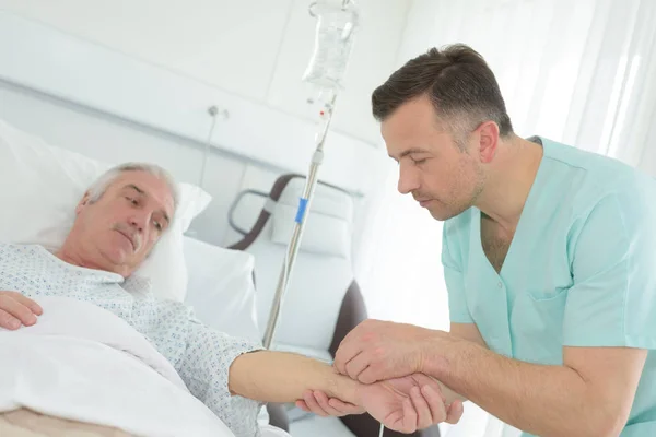 男性护士把静脉滴入病人手臂 — 图库照片