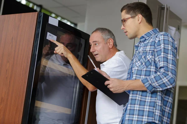 Mannen kijken naar identificatie sticker op machine — Stockfoto