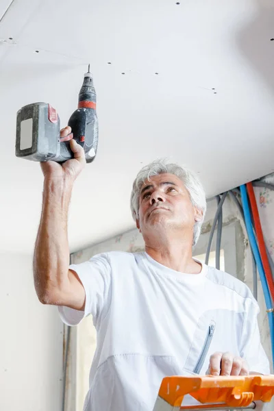 Costruttore Utilizzando Cacciavite Elettrico Sul Soffitto — Foto Stock