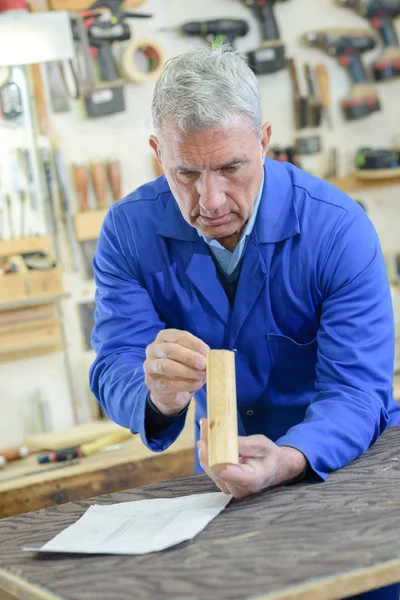 Starszy Człowiek Inspekcji Kawałek Drewna Warsztacie — Zdjęcie stockowe