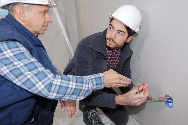 Dos constructores que trabajan con electricidad en interiores —  Fotos de Stock