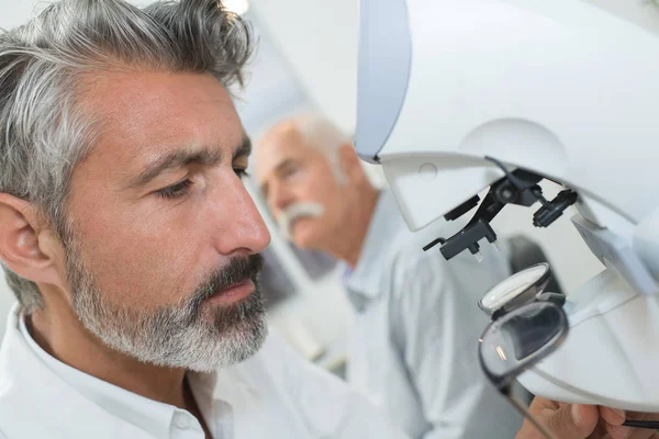 Retrato de cientista masculino adulto médio usando microscópio em laboratório — Fotografia de Stock