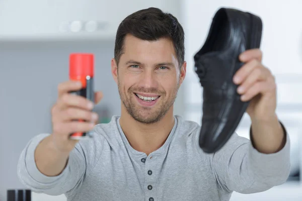 Fröhlicher Mann zeigt Schuhe und Polierer — Stockfoto