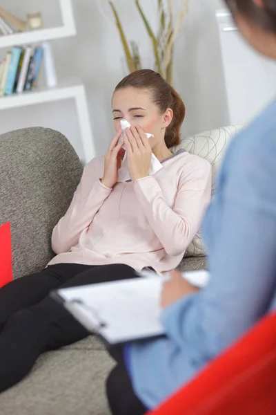 Jonge vrouw blazen neus met servet en arts thuis — Stockfoto