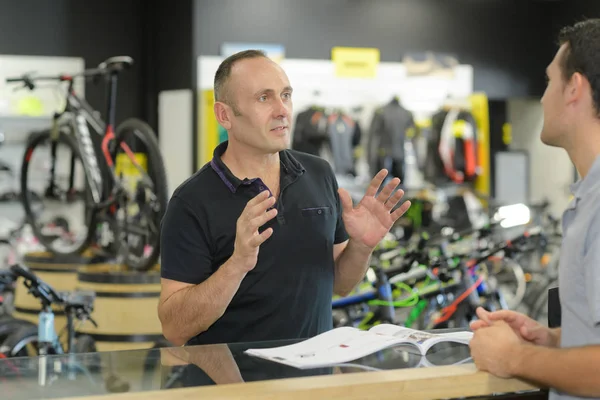 Чоловік Працює Магазині Прокату Велосипедів Розмовляючи Клієнтом — стокове фото