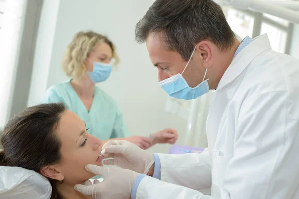 歯医者は歯医者で患者の歯を調べる — ストック写真