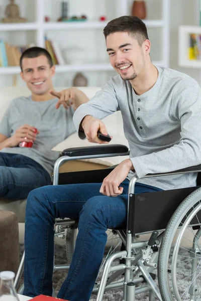 Młodych Ludzi Jeden Wózku Inwalidzkim Oglądanie Telewizji Śmiejąc Się — Zdjęcie stockowe