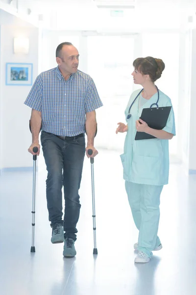 男性病人与演员在医院走廊散步 — 图库照片