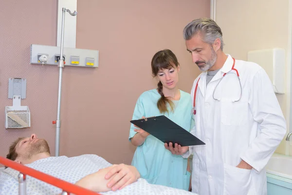 Arzt Liest Klemmbrett Mit Kollege Bereitet Patient Auf Vor — Stockfoto