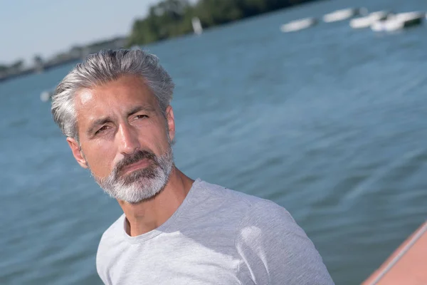 Pohledný muž pózuje před plachetnice a jezero — Stock fotografie