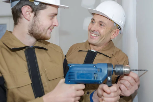 Eletricista no local de construção aprender a perfurar — Fotografia de Stock