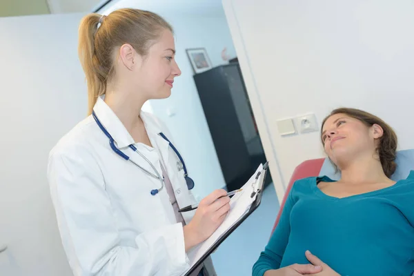 Молодая беременная женщина с врачом в больнице — стоковое фото