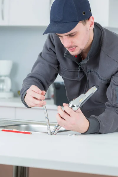 Plumber fixing water tap in kitchen — Stock Photo, Image